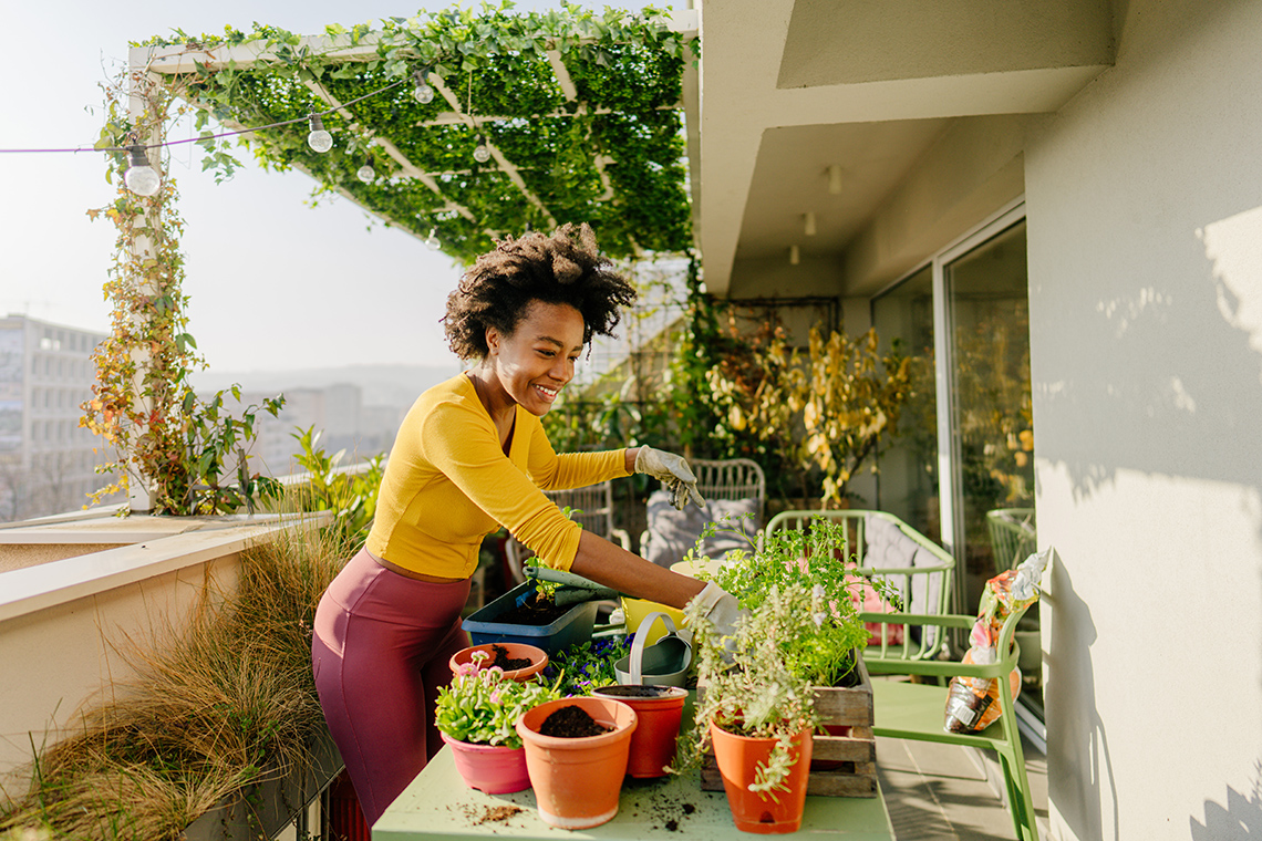 A person attending to plants in pots on their rooftop balcony.