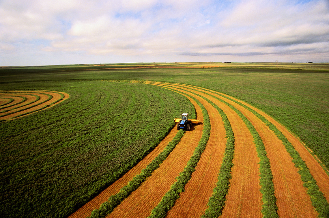 A farmer harvesting a field in a tractor.