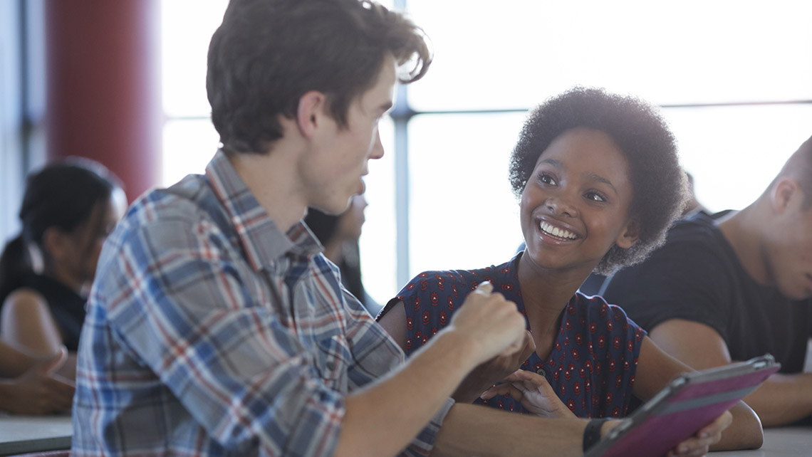 Two people discussing while sitting at a table together.