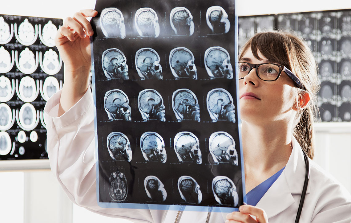 A doctor looking at a scan providing images of different views of a brain.