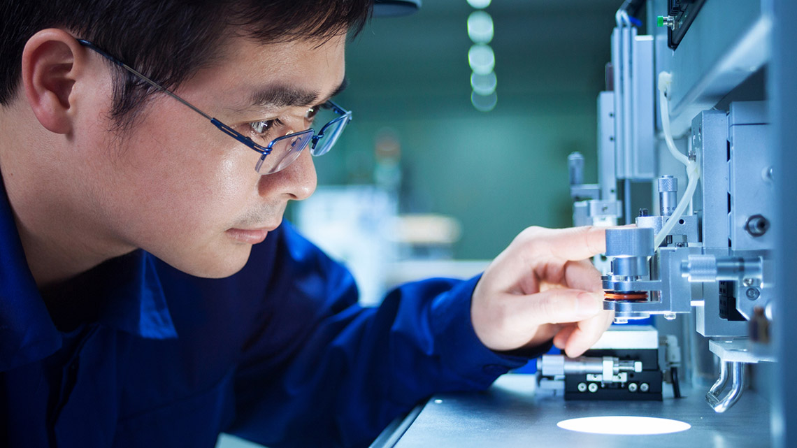 A person adjusting a microscope.