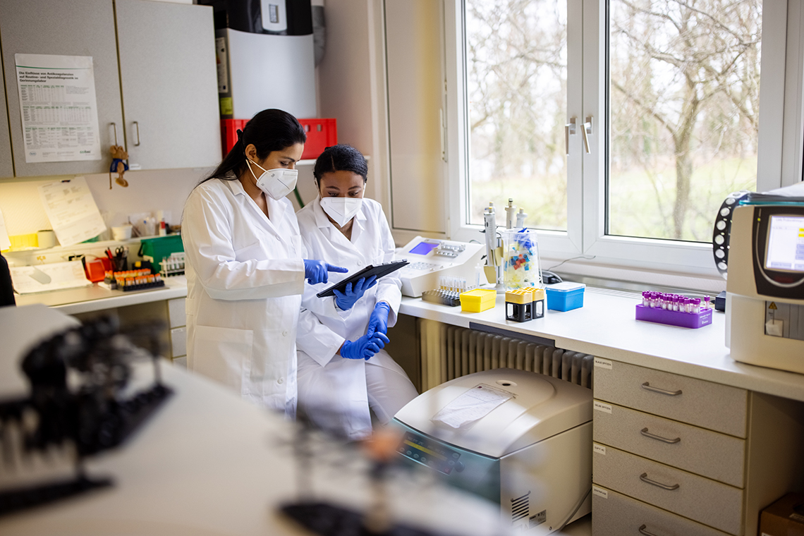 Two people wearing masks and working in a lab.