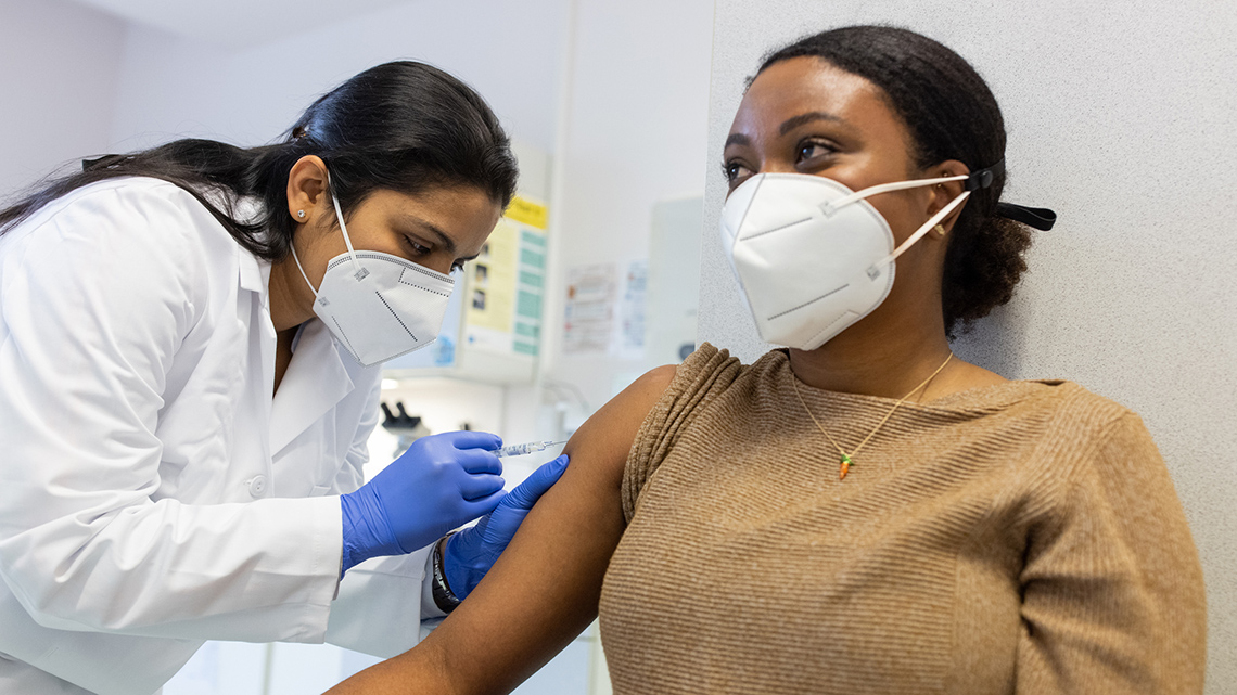 Young woman being vaccinated by a doctor