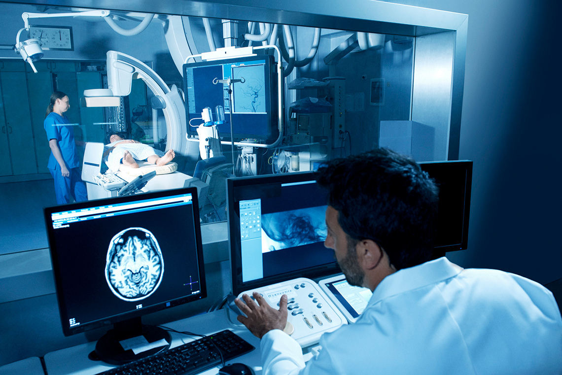 A technician examining a CT scan on a computer.