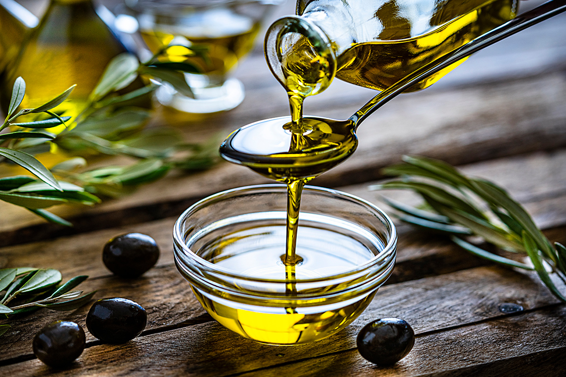 Olive oil being poured into a glass bowl.