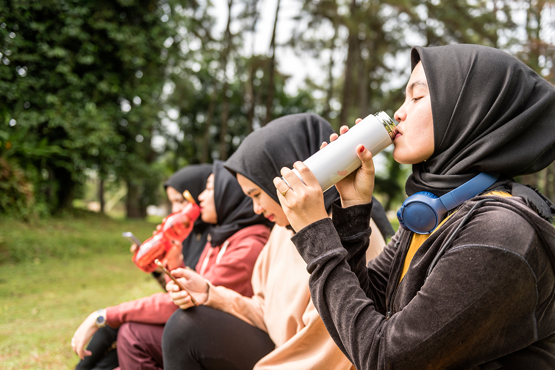 People drinking water from their reusable water bottles.