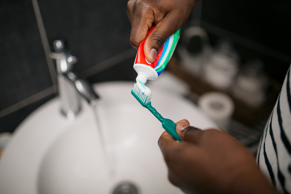 A person putting toothpaste on their toothbrush.