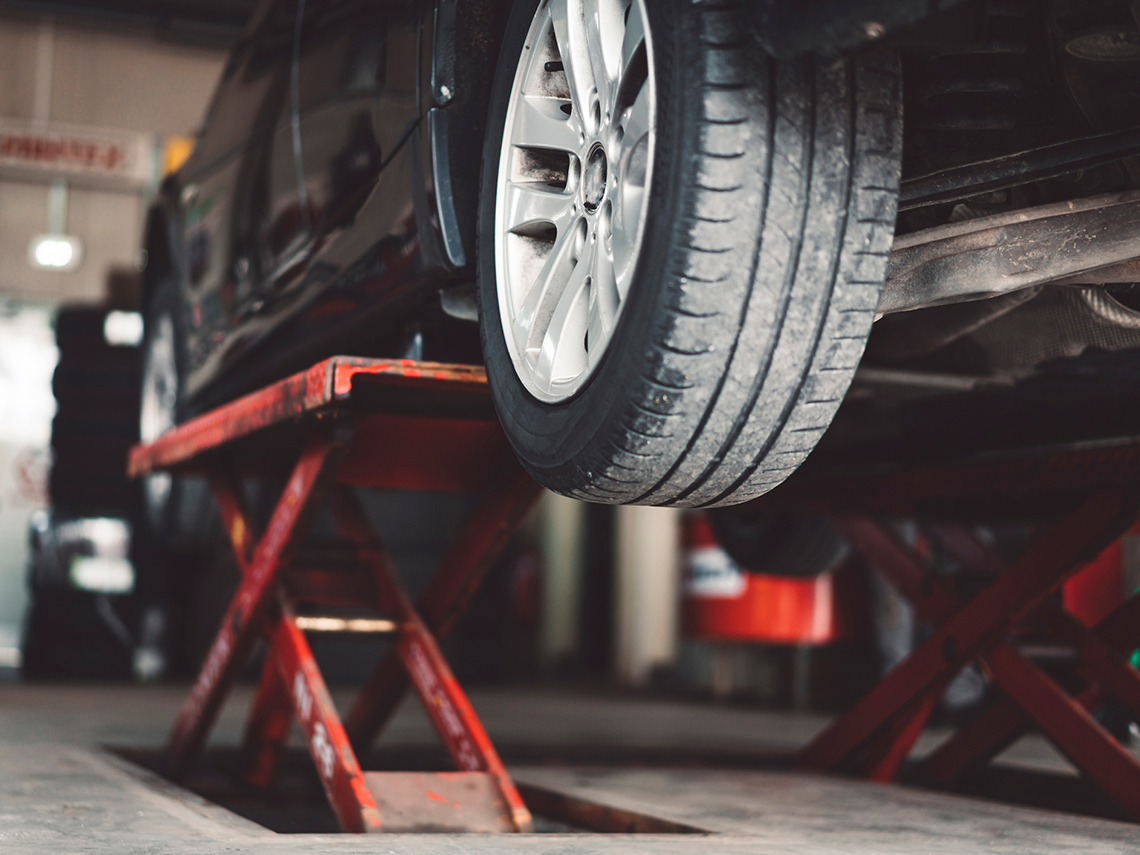 A car lift underneath the body of a car, lifting up the car.