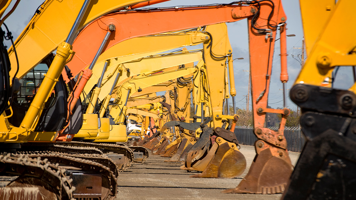 A row of excavating machines lined up beside each other on an excavation site.