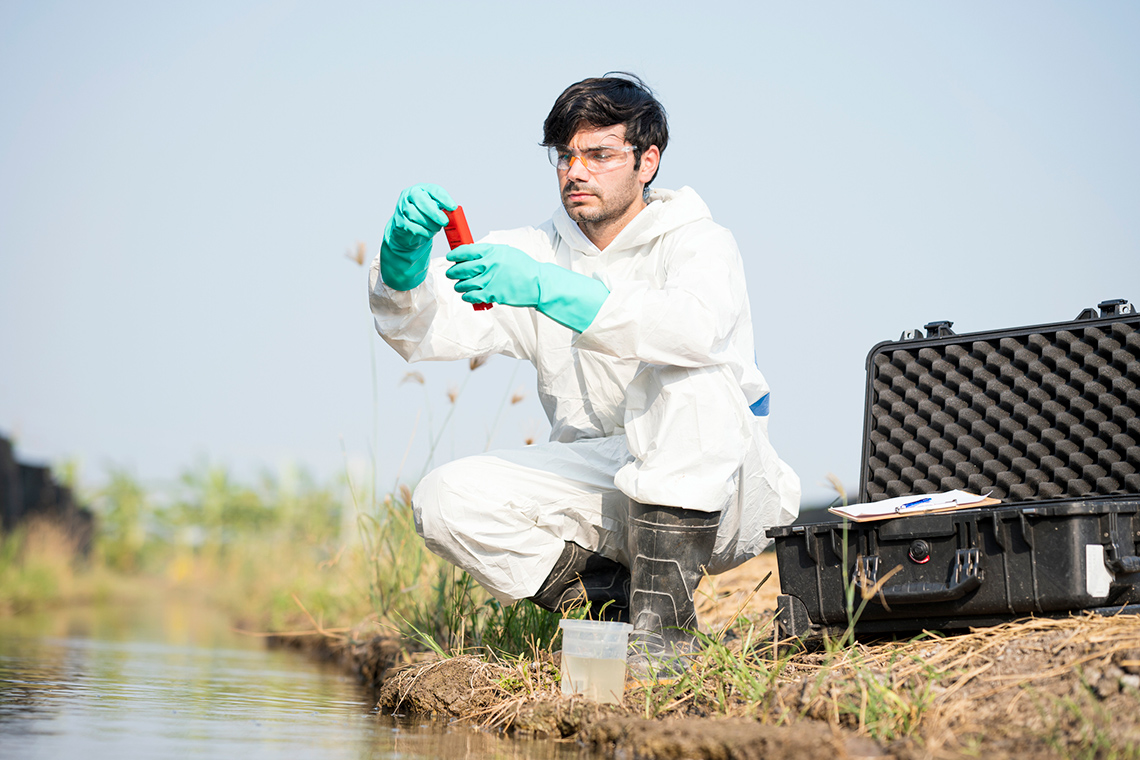 A chemical engineer testing some water at a pond.