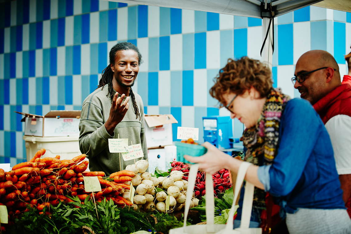 People purchasing vegetables at a farmers market.