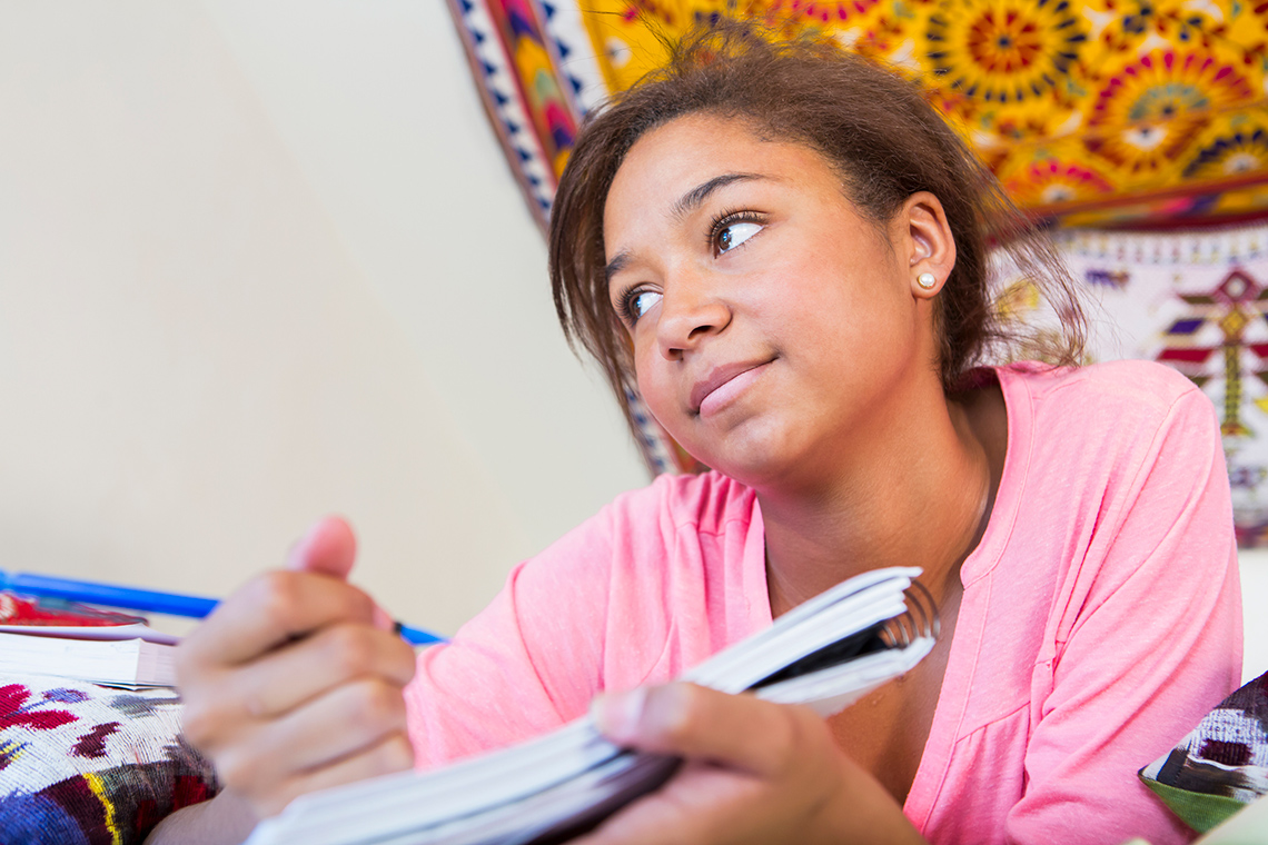 A student thinking while they write in their notebook.