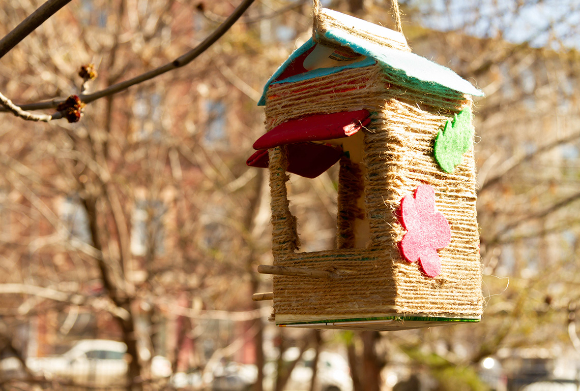 A bird feeder made from a drink carton wrapped in twine rope.
