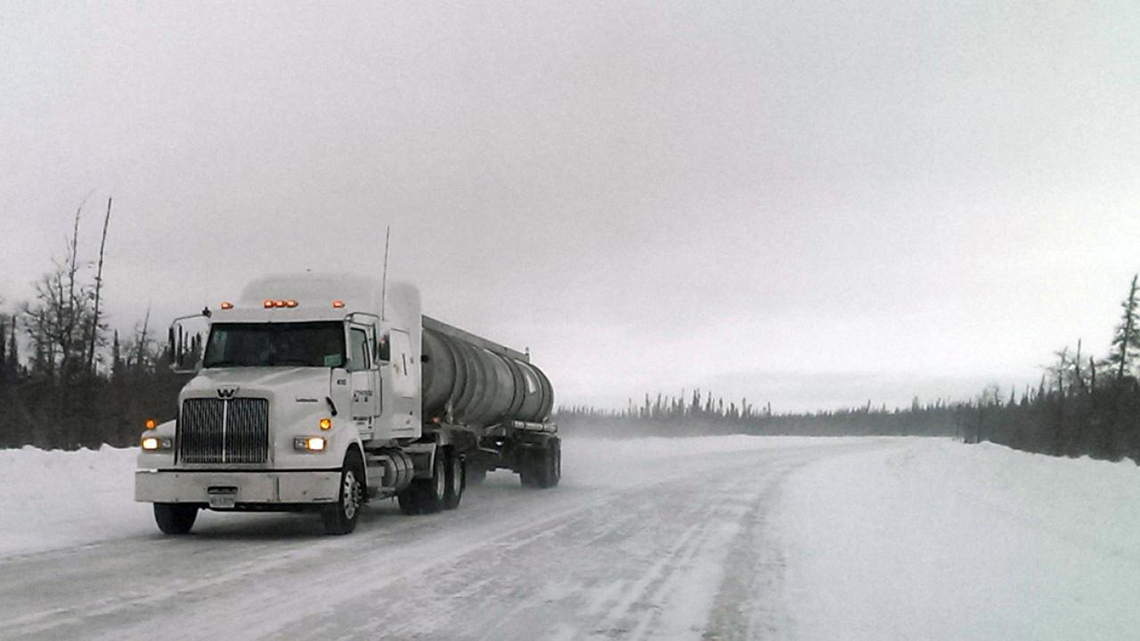 A transport truck driving along an icy road.