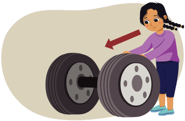 A learner rolling a wheel and axle, shown here as two tires attached in their centres by a bar.