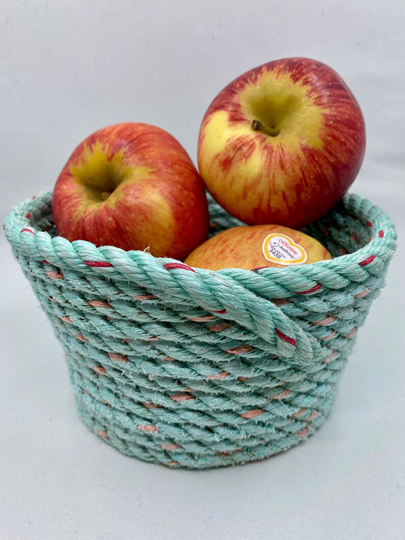 Repurposed fishing rope basket holding apples.
