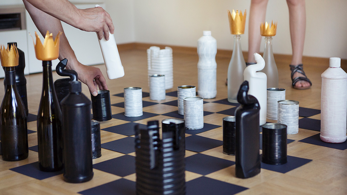 A game of chess with the game pieces made from upcycled cans and bottles.