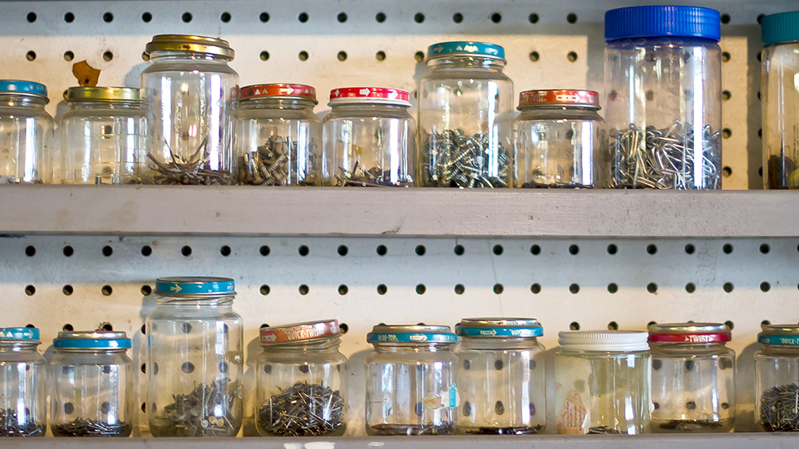There are glass jars being used to hold items such as nails and screws.