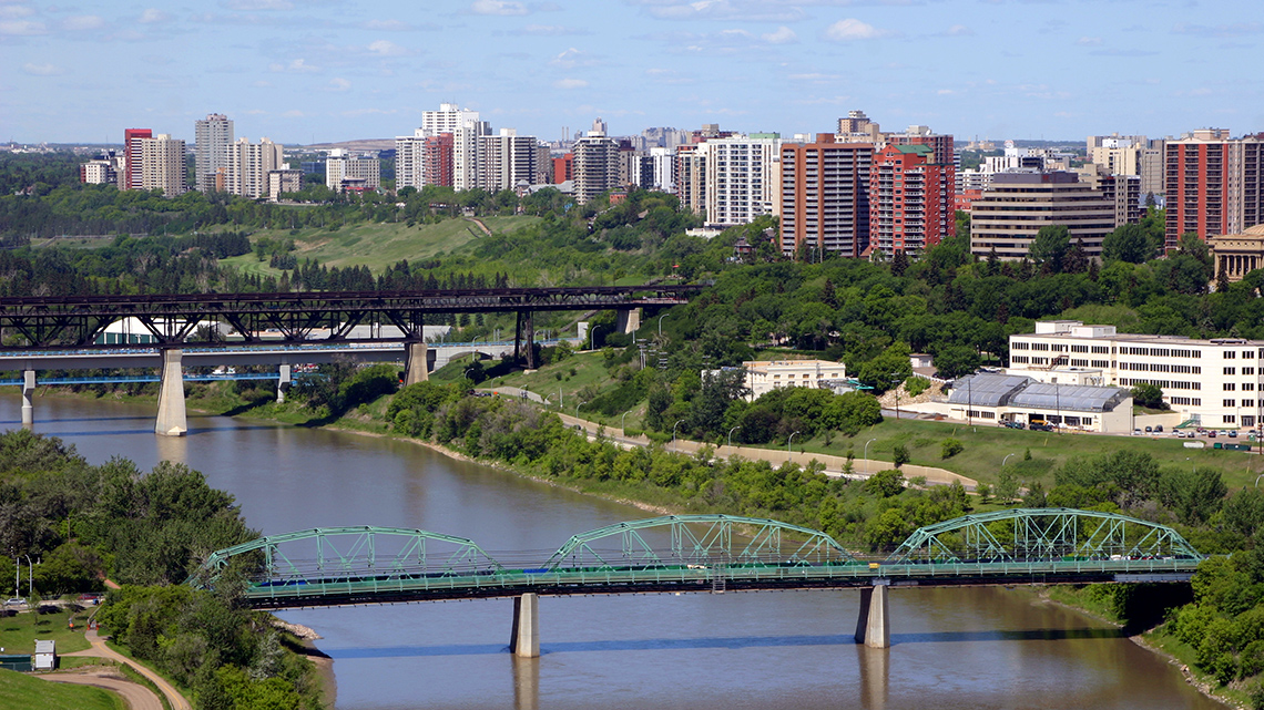 Two bridges crossing over a river into a town. 