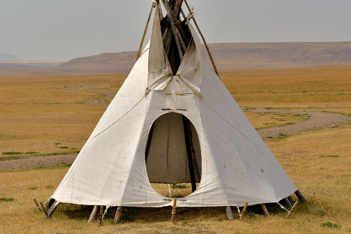 Wooden poles arranged in a cone shape wrapped in fabric.