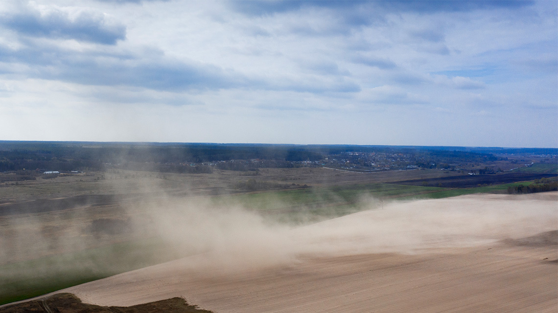 Wind Erosion Wind blows a large cloud of dust across a dry farm field.