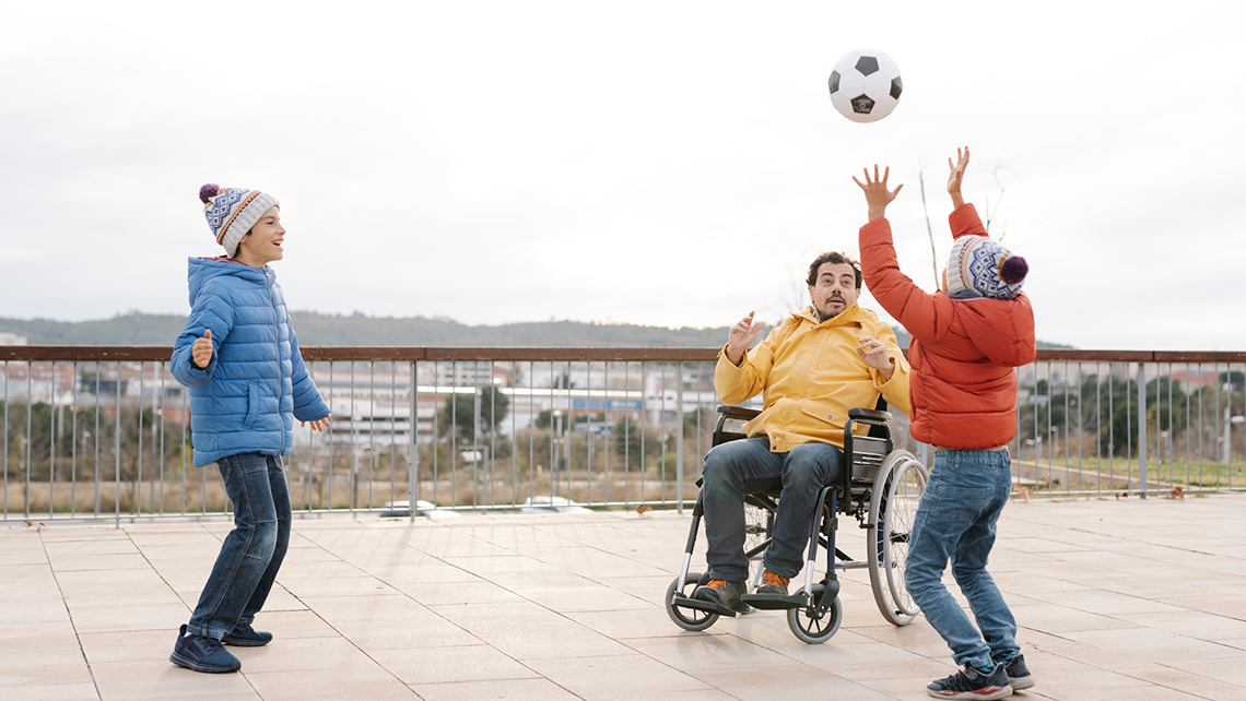 Two children and an adult throwing a ball into the air.