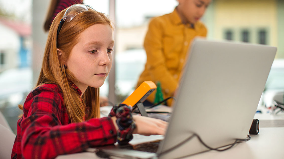 A student debugging code for a robot on a computer.