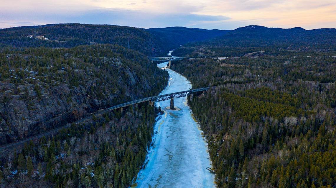 An arch bridge over a river that feeds into a large lake.