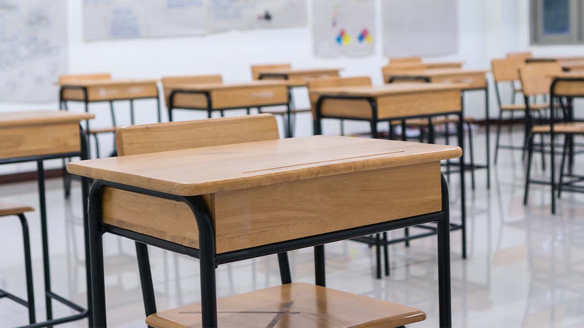 Desks with wooden tops and metal legs in a classroom.