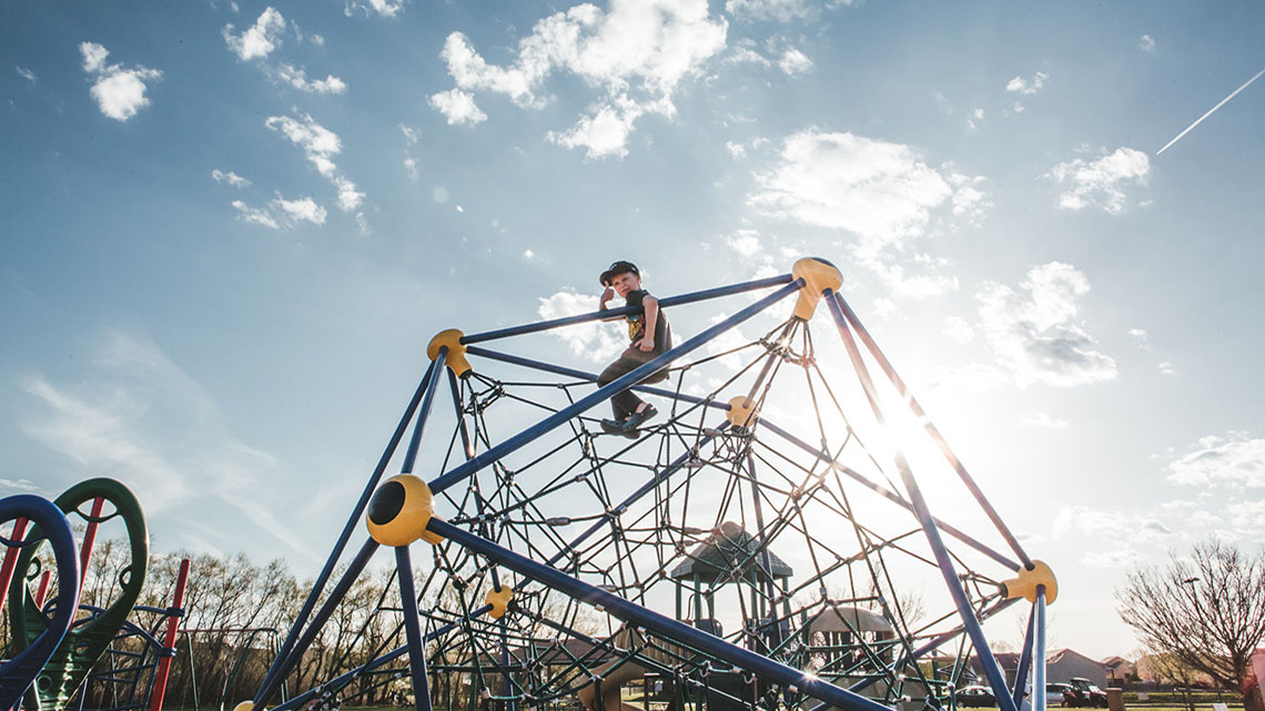 A playground climbing structure made of large equilateral triangles with rope netting in the middle.