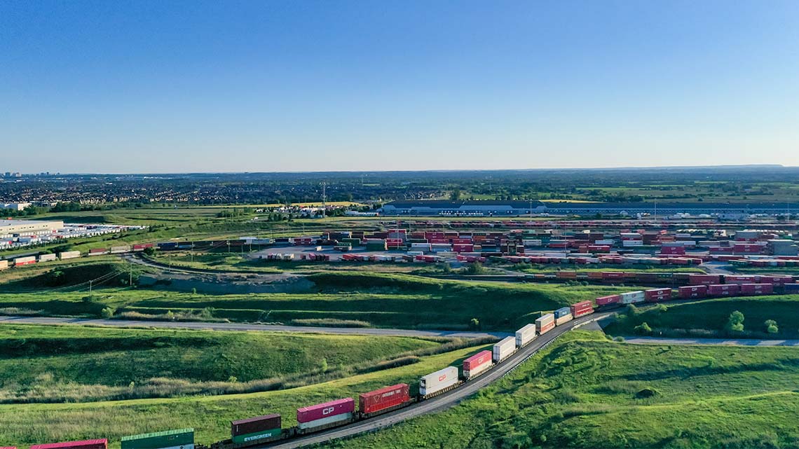 Aerial view of a train travelling towards a railway terminal where many other trains are parked.