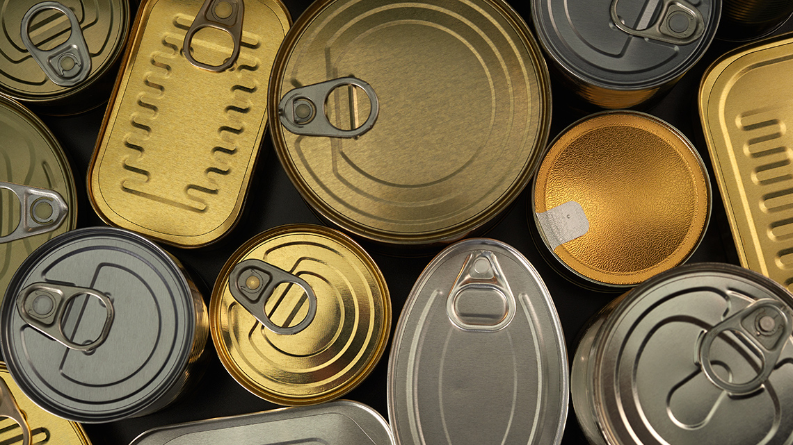 A top view of an assortment of aluminum cans in various sizes and shapes. Many tops of the cans have a tab that you pull to open the can.