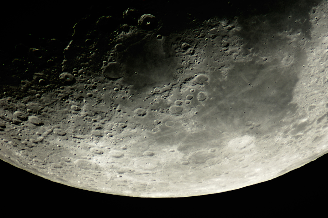 A closeup of the moon’s surface partly in shadow and partly reflecting sunlight.