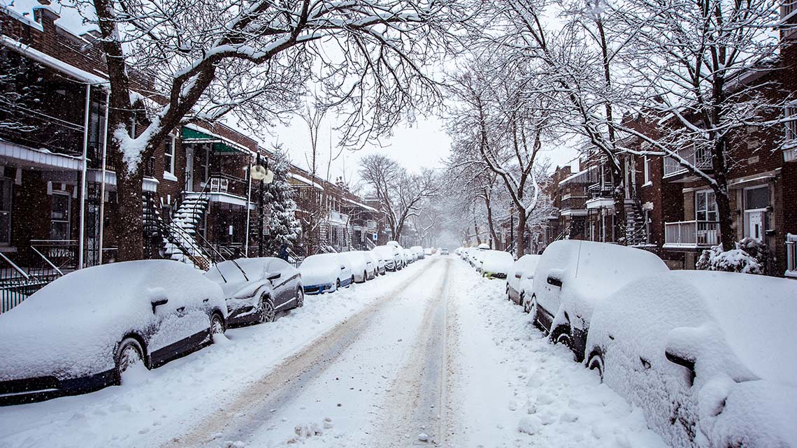 Cars on a street covered in snow.