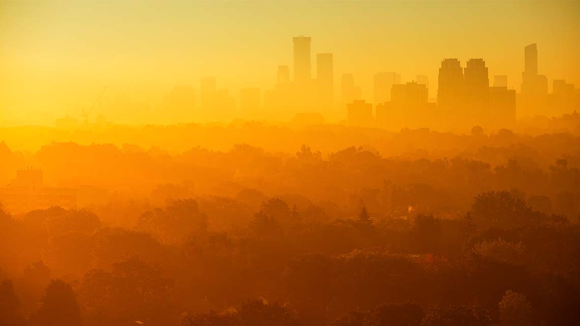 Heavy orange and yellow smog covering a city skyline.