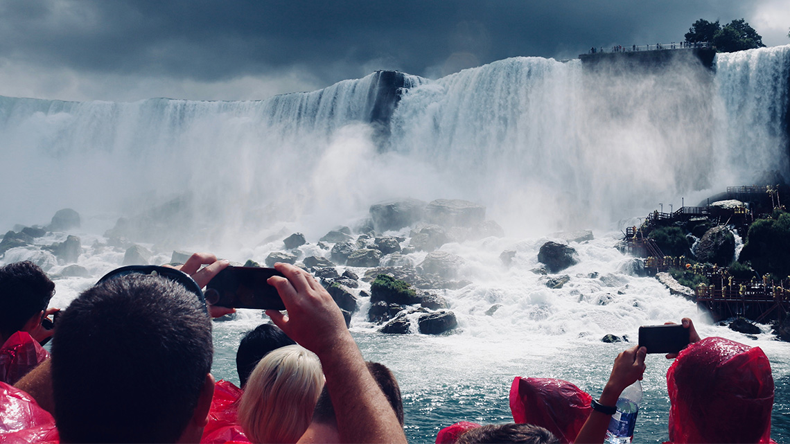 People taking photographs from a tourist boat that moves along the bottom of Niagara Falls.