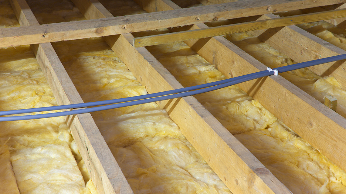 A layer of insulation beneath the slat wood frame of a floor.