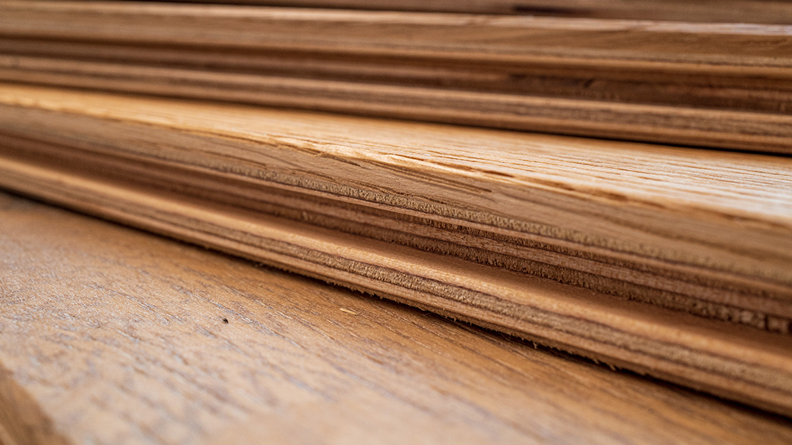 A stack of engineered hardwood flooring. The flooring is made up of many thin layers of wood.