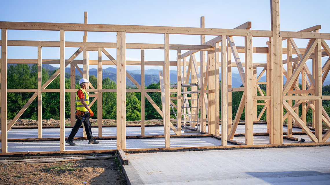 A person walking through the first-floor wood frame of a house.