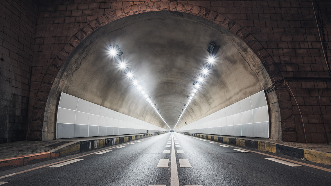 An arch created out of bricks forms the entrance to a road tunnel.