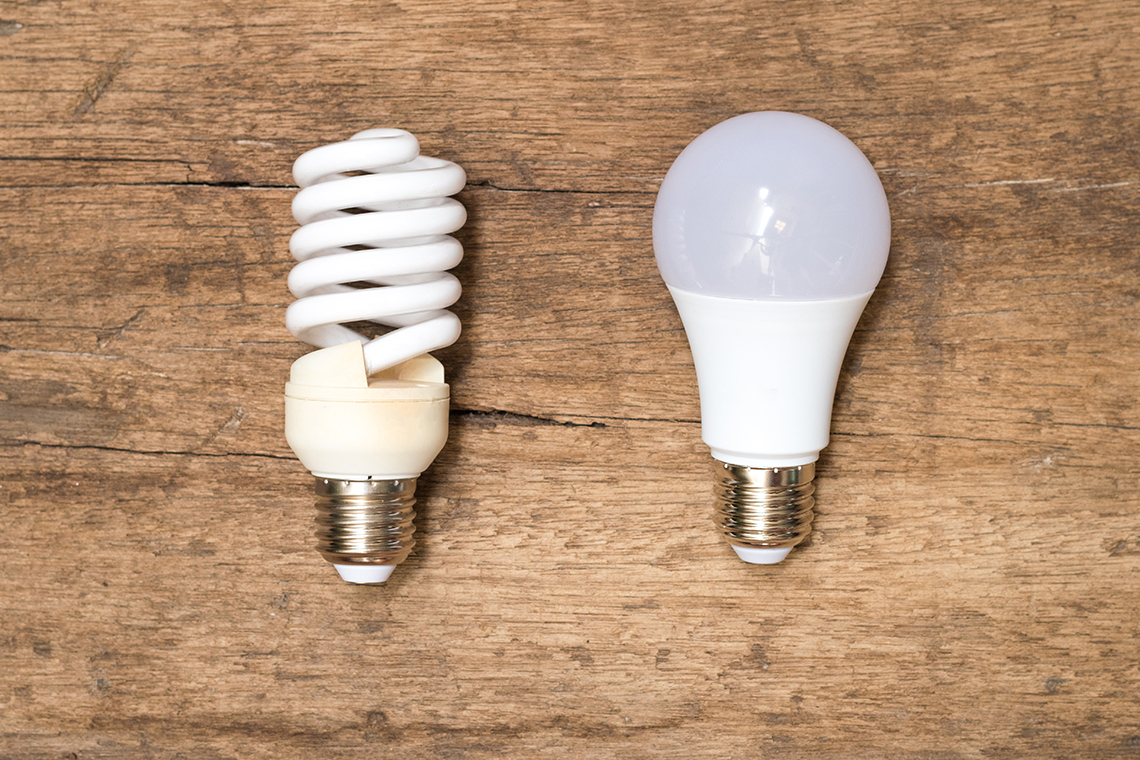 An image of a fluorescent bulb beside an LED bulb on a table top.