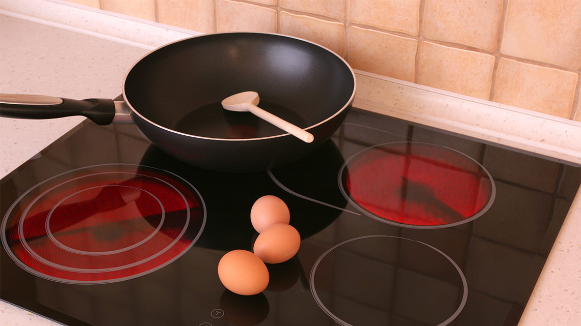 A cooking pot sitting on a cooktop stove with some eggs.