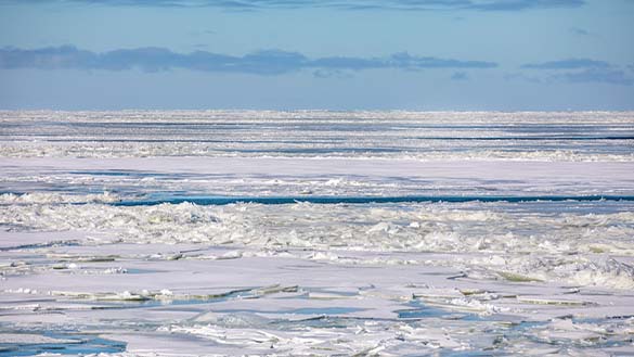 Frozen Lake Erie with ice and snow on the lake with a clear blue sky.