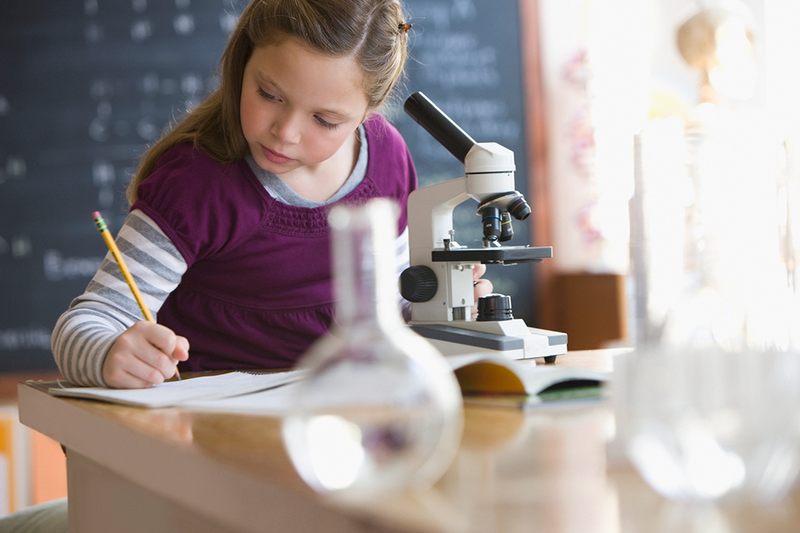A student recording information in their notebook after using a microscope.