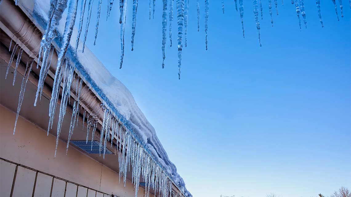 There are thick and thin icicles hanging from a structure.