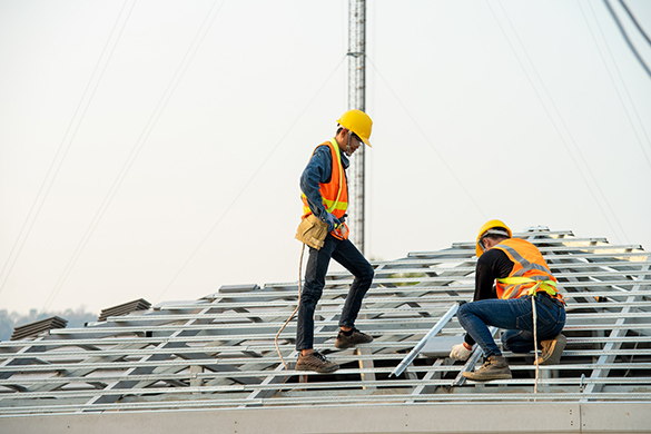 Two construction workers building a roof.