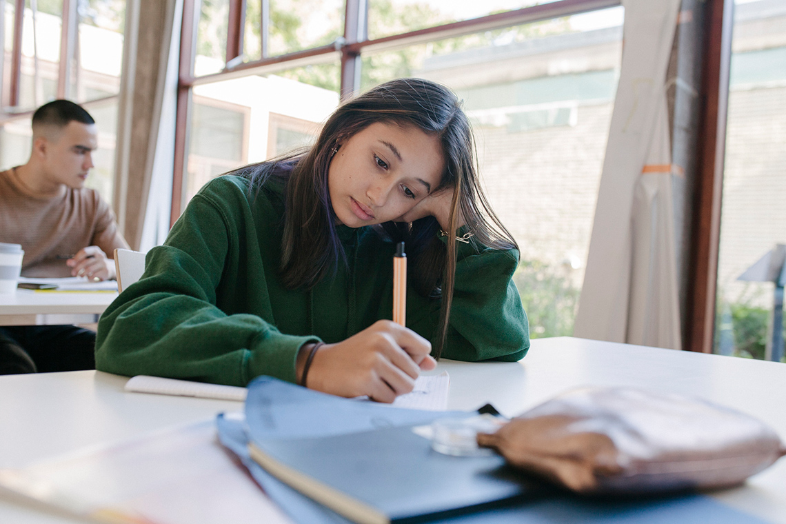 A student writing in their notebook. 