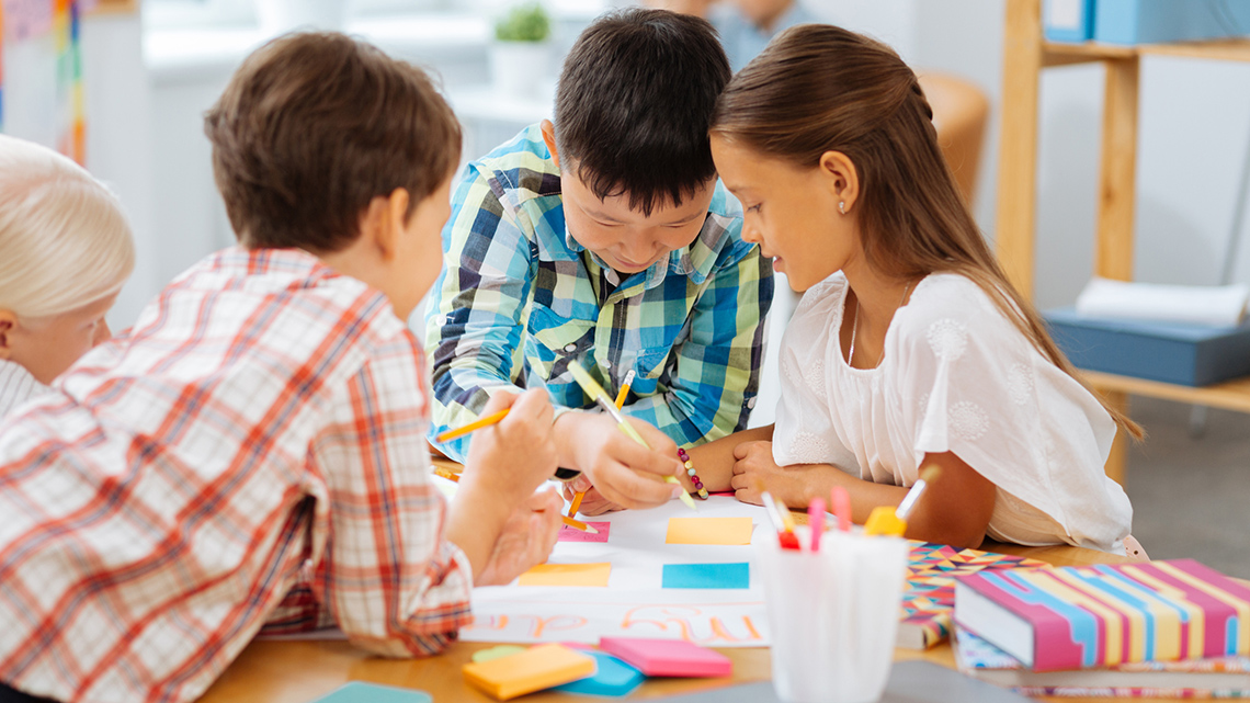 Four children at a table working on a project together.