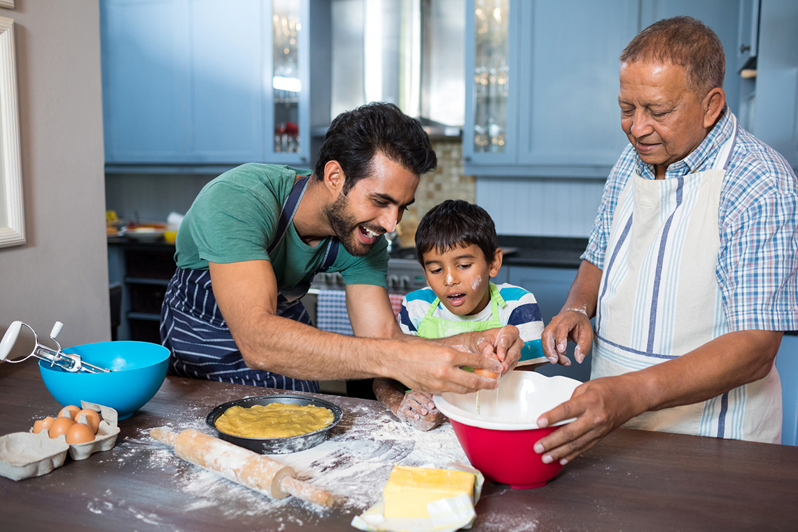 Two male adults and a young boy cooking.