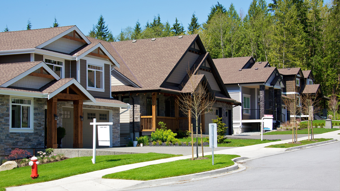 A road with several houses for sale in a medium-sized town.